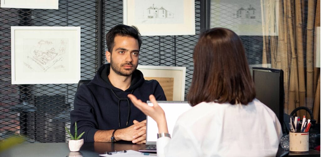 zwei Personen stellen sich in einem Mitarbeitergespräch Fragen